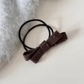 Détail d'un élastique à cheveux nœud marron à pois sur un fond minimaliste doux - Cravate à cheveux / Marron