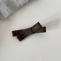 Détail d'une pince à cheveux nœud marron à pois avec une texture mate style français - Barrette / Vert