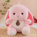 Detailed macro shot of a soft pink plush rabbit toy with a brand tag on a woven mat - Pink Rabbit / 23cm