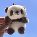 Primo piano di un portachiavi in peluche a forma di panda marrone e bianco contro il cielo - Panda Marrone Seduto / 13cm (Con Cordino)