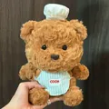 Gros plan d'un ours en peluche marron avec une toque de chef et un tablier rayé - Ours Chef Brun (1) / 22cm