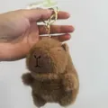 A hand holding a cute brown plush capybara stuffed animal keychain with a gold ring - Plain Capybara / 10cm