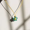 Detail einer grünen Blumenkette, die einen Schatten auf weißen Hintergrund wirft - Grünes Blütenblatt Gelbe Kordel / Grün