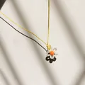 Nahaufnahme einer süßen gelben Kette mit einem kleinen Blumenanhänger aus Acryl. - Beige