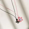 Nahaufnahme einer rosa Blumen-Halskette mit blauer Perle an einer rosa Kordelschnur. - Rosa Blütenblatt Blauer Kern Rosa Kordel / Wassermelonenrot
