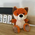 Adorable orange fox plush toy sitting on a wooden desk next to a desktop calendar. - Height 25cm / Orange Fox
