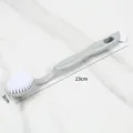 Grey plastic shoe cleaning brush featuring soft white bristles, 23cm total length detail view - Gray