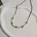 Close-up van groene madeliefjesketting met witte parels en zilveren kettingdetail. - Vijf Madeliefjes Kralen Ketting / 45+5cm
