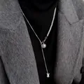 Dettaglio di una collana regolabile con perle e catena serpente su un cappotto di lana grigio. - Perlina Bianca Regolabile con Sfera in Acciaio