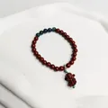 Eleganter Armband mit roten Zinnoberperlen für Damen und kleinem geschnitztem Mönchsanhänger - Gott des Reichtums Stil