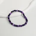 Detailaufnahme eines 6mm lila Amethyst-Perlenarmbands auf einem weißen Display-Ständer - Traubenlila