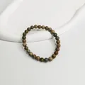 Nahaufnahme eines 6 mm Naturstein-Perlenarmbands in Erdtönen auf einem weißen Tablett - Tigerauge Braun