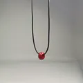 Primo piano di una perla in pietra naturale rossa su una collana di cordino nero - Cordoncino Cerato Cerchio Rosso / 45+5cm