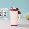 Detailansicht eines 316 Edelstahl-Kaffeebechers in Creme mit roten Akzenten und Band - 500ml / Rot