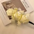 Close-up detail of a retro creamy yellow satin rose hair bun maker with elegant bows - 3 Large Roses Style / Off White