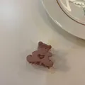 Gros plan d'une pince à cheveux mate rose poudré en forme d'ours avec un cœur évidé - Rose Crème