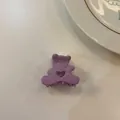 Gros plan d'une pince à cheveux violette en forme d'ours sur fond blanc. - Violet