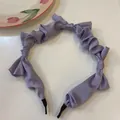 Macro shot showing the texture of a purple pleated satin headband with decorative bows - Purple