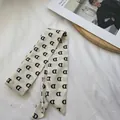 Gros plan d'une écharpe en soie avec motif de lettre D noire sur tissu crème - 80-100cm / Blanc