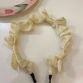 Close-up detail of a cream satin headband featuring elegant ruffles and multiple bow accents - Off White
