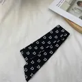 Détail d'une écharpe en soie noire avec imprimé lettre D blanche sur fond en tissu - 80-100cm / Noir