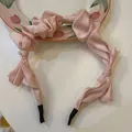 Detailed view of a pink satin bow headband with elegant ruffled design on a plate - Pink