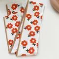 Gedetailleerd zicht op het oranje bloemmotief op een witte zijden haarsjaal lint. - 80-100cm / Oranje Bloemen