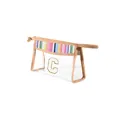 Detailed view of clear PVC makeup bag featuring rainbow woven trim and a gold 'C' patch - Rainbow with White Letter / S