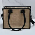 Detailweergave van jute draagtas met zwarte bies en een afneembare schouderriem. - S