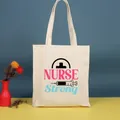 Bolso de lona beige con un diseño gráfico impreso de 'NURSE Strong' - 35*39cm / Nurse-1