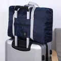 Navy blue foldable waterproof travel bag attached to a silver rolling suitcase handle. - Second Generation / Navy Blue