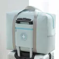 Large capacity waterproof foldable travel bag in light blue shown on a suitcase handle - Round Logo Bag / Blue