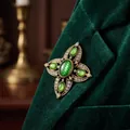 Elegante spilla a croce smeraldo vintage appuntata sul risvolto di un blazer di velluto - Oro Antico, Verde Smeraldo