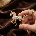 Elegante spilla a forma di cavallo dorato con strass bianchi luccicanti - Zodiaco Cavallo / Oro