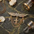 Elegant golden wing brooch with inlaid rhinestones and dangling crosses on marble - Gold Wings
