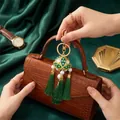 Detail showing a Chinese-style green embroidered ball and tassel charm on a handbag. - Keychain / Green