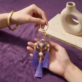 Detail of a purple embroidered ball keychain with long silk tassels and pearls. - Keychain / Purple