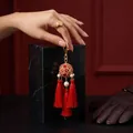 Close-up of a traditional Chinese red embroidered ball tassel keychain with gold finish - Keychain / Red