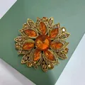 Makro-Detail einer Vintage-Blumenbrosche aus orangem Glas mit goldener Textur-Oberfläche - Kaffeebraun