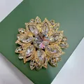 Nahaufnahme einer Vintage-Kristallblumenbrosche mit Goldfassung auf einer grünen Geschenkbox. - Weiß
