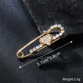 Close-up of golden safety pin brooch with sparkling heart-shaped rhinestone inlay. - Heart Pin Design (XD825340) / 3.7cm x 1.8cm / Gold
