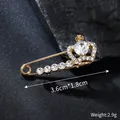 Detailed view of an elegant gold crown brooch pin with rhinestones, size 3.6x1.8cm - 3.6cm x 1.8cm
