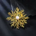 Elegant gold snowflake brooch detail featuring a large center pearl on black silk. - Gold & White Pearl Snowflake