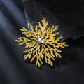 Close-up macro view of a luxury gold snowflake brooch featuring a dark grey pearl center - Gold & Grey Pearl Snowflake