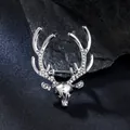 Close-up of silver deer head brooch with sparkling rhinestone antlers on a dark rock. - Silver