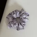 Detail macro view of a lavender satin scrunchie featuring a white bow pattern design. - Hair Tie / Purple