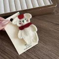 Detailaufnahme einer süßen weißen Bären-Haarklammer mit rotem Apfel und Schal - Roter Schal Bären Haarnadel