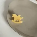Détail macro d'une petite pince à cheveux en acétate en forme de cheval à bascule - Design de cheval en bois / Pince Cheval Jaune