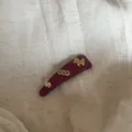 Detailopname van de bordeauxrode haarspeld met goudkleurige paarden- en muntbedeltjes. - Driehoekige Haarclip (1# Paard) / Rood