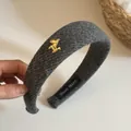 Close-up of gray knitted headband with golden horse charm and hand made label - Style 3 Gray Striped Horse Headband